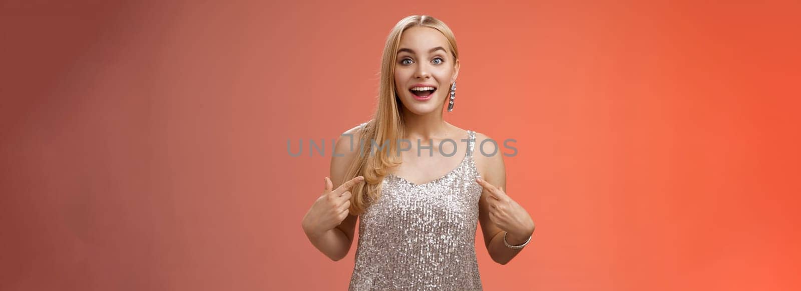 Surprised wondered happy blond charming cheerful woman in glittering silver dress pointing herself amused thrilled picked be chosen participate awesome event, standing joyful red background.