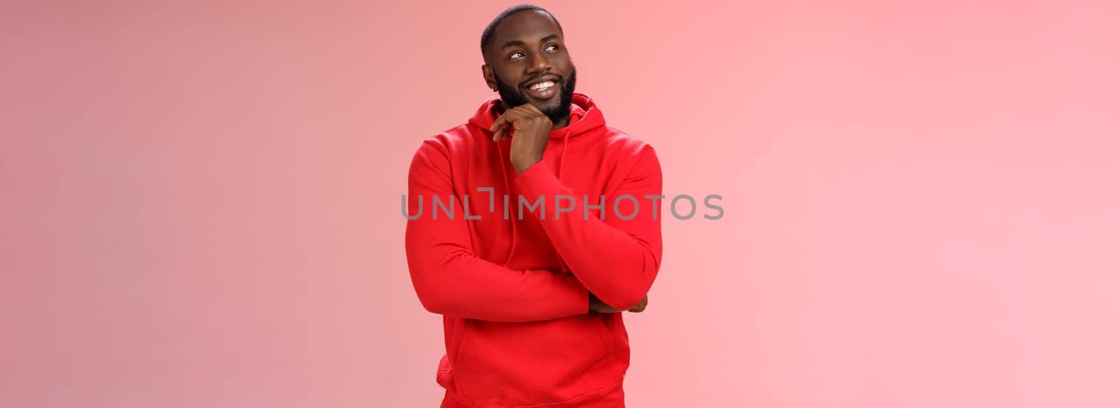 Inetersted successful young black sportsman considering take opportunity look curious upper left corner thinking touch chin thoughtful, make decision choosing what pick, pink background.