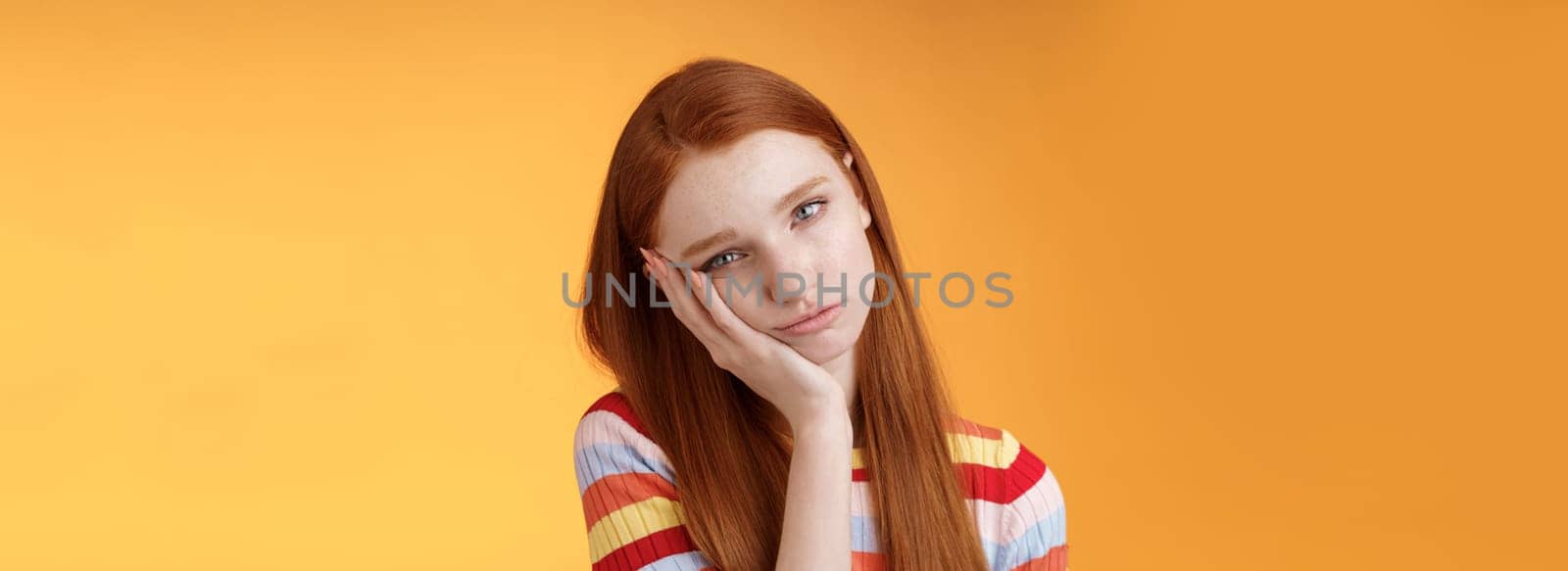 Indifferent careless sleepy redhead silly female student lean palm looking bored uninterested listen lame stories wanna escape standing exhausted lacking interest, posing orange background.