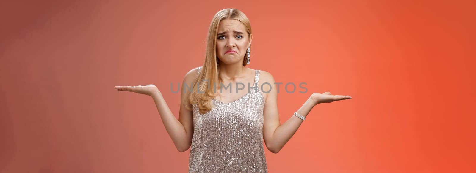 Upset clueless frustrated blond european young girl in glittering silver evening dress grimacing pouting sad shrugging raise hands sideways dismay doubtful, no idea what do, complicated decision.