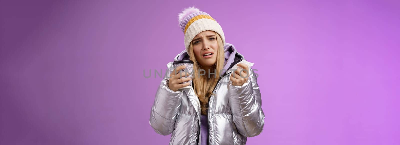 Lifestyle. Upset dizzy cute blond girl got sick feel unwell grimacing hold hot tea take-away cup tissue sneezing suffering high temperature runny nose headache standing uncomfortable bad purple background.