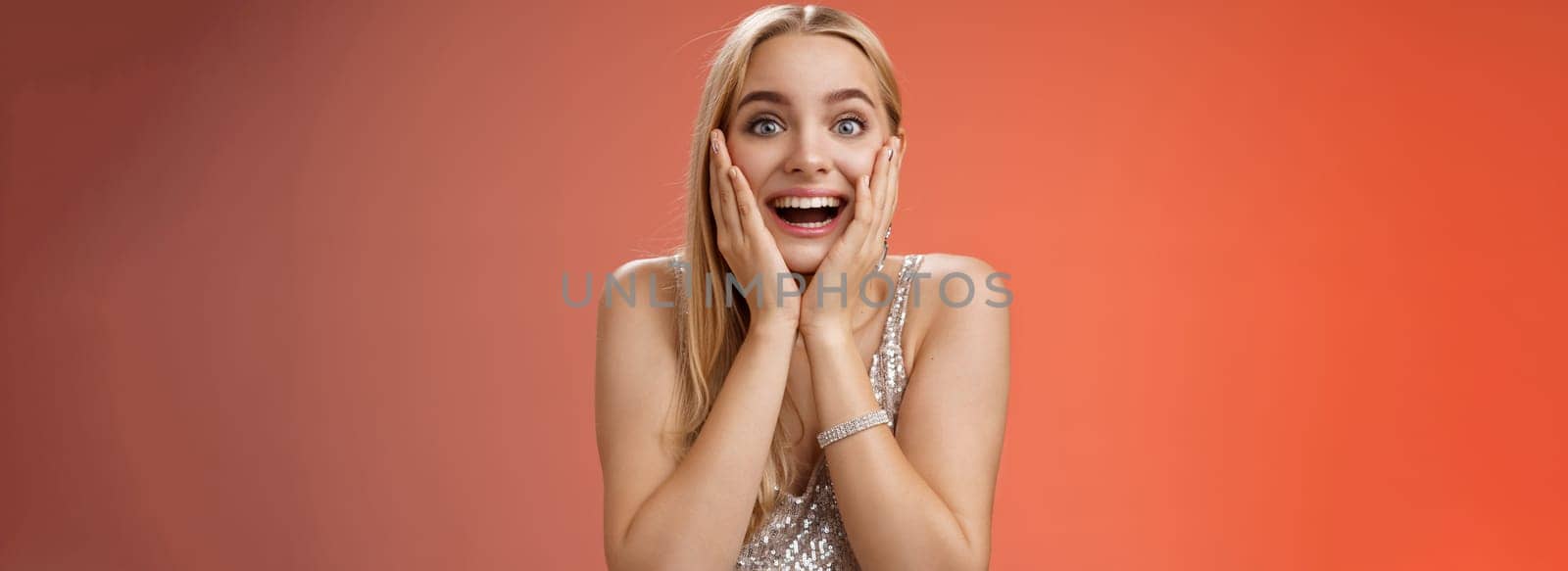 Amazed speechless excited attractive young woman blond long hair press palms cheeks blushing amused cannot believe see popular super star glancing thrilled amazement, surprised red background.