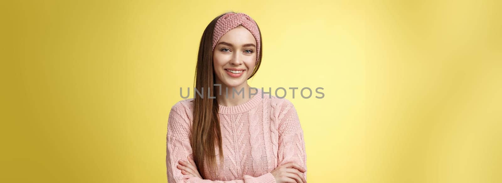 Waist-up shot of confident creative joyful cute european female model in knitted pink sweater, headband, cross arms self-assured, satisfied, smiling pleased and motivated, looking delighted.