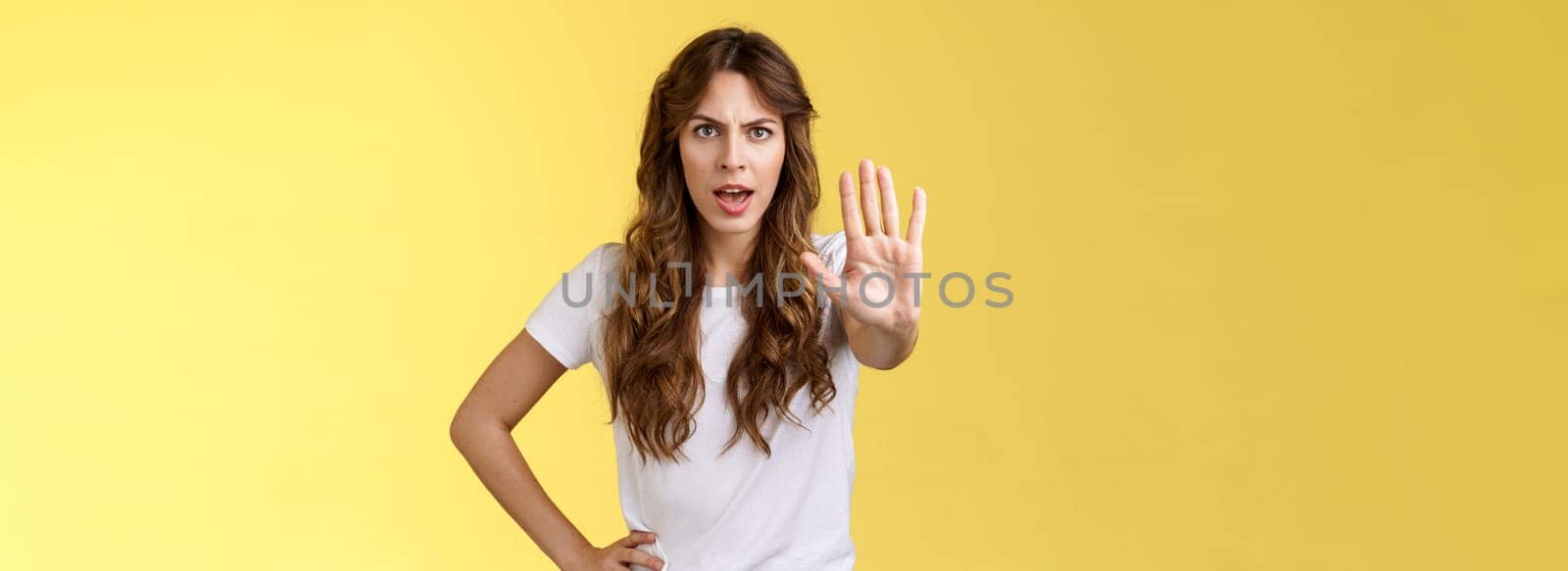 Stop right there fashion police. Serious-looking confident young curly-haired girl pull hand enough prohibition gesture demand end situation forbid friend drive stand yellow background by Benzoix