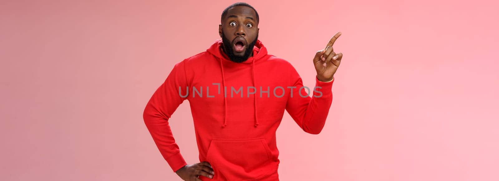 Lifestyle. Shocked astonished black bearded young guy drop jaw gasping speechless pointing upper left corner widen eyes impressed cannot believe saw miracle look camera questioned unbelievable sales.
