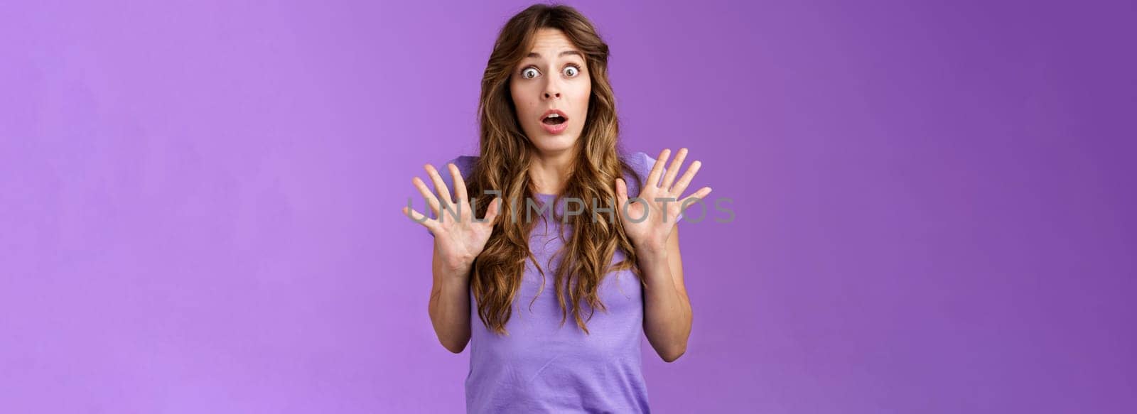 Ambushed shocked girl gasping not expect friend jump out corner raise palms surprised astonished drop jaw open mouth stunned stare camera impressed stupefied purple background. Copy space