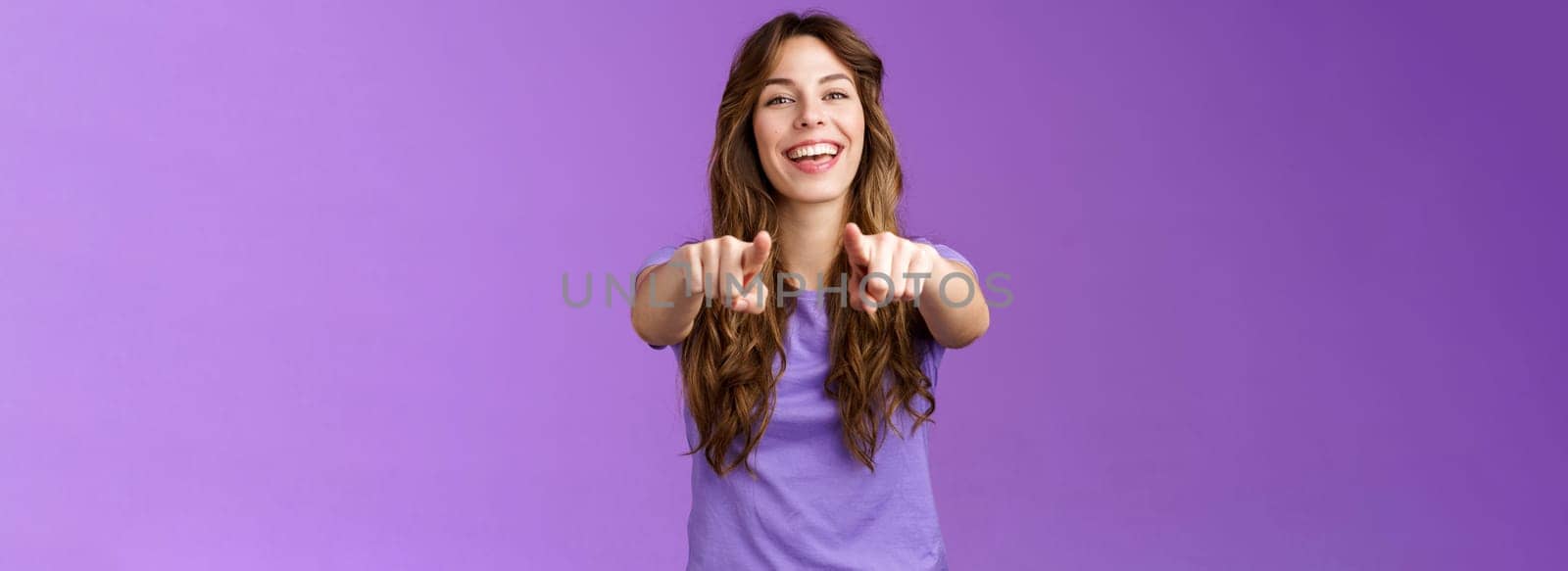 Its you. Friendly glad joyful happy curly-haired girl pointing fingers camera smiling broadly laughing congratulate friend singing song indicating boyfriend make choice stand purple background by Benzoix