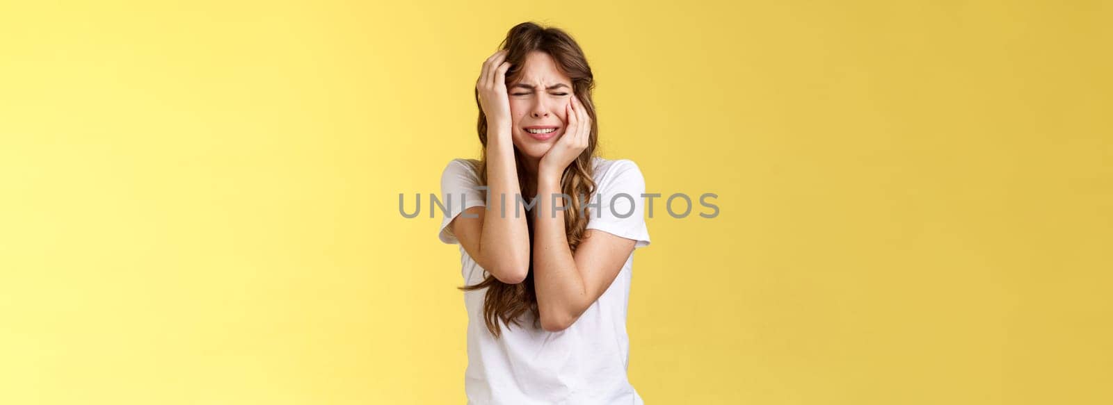Offended silly timid insecure girl crying feel scared insulted close eyes whining grab head being victim sorry herself after huge quarrel sobbing stand yellow background upset distressed. Lifestyle.