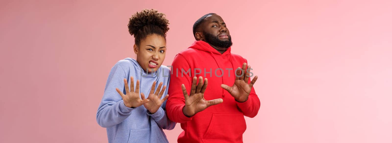 Studio shot pair african american friends woman man cringing disgust dislike feel awkward reluctant step back raise palms defensive refusing rejecting try stinky product, standing pink background.