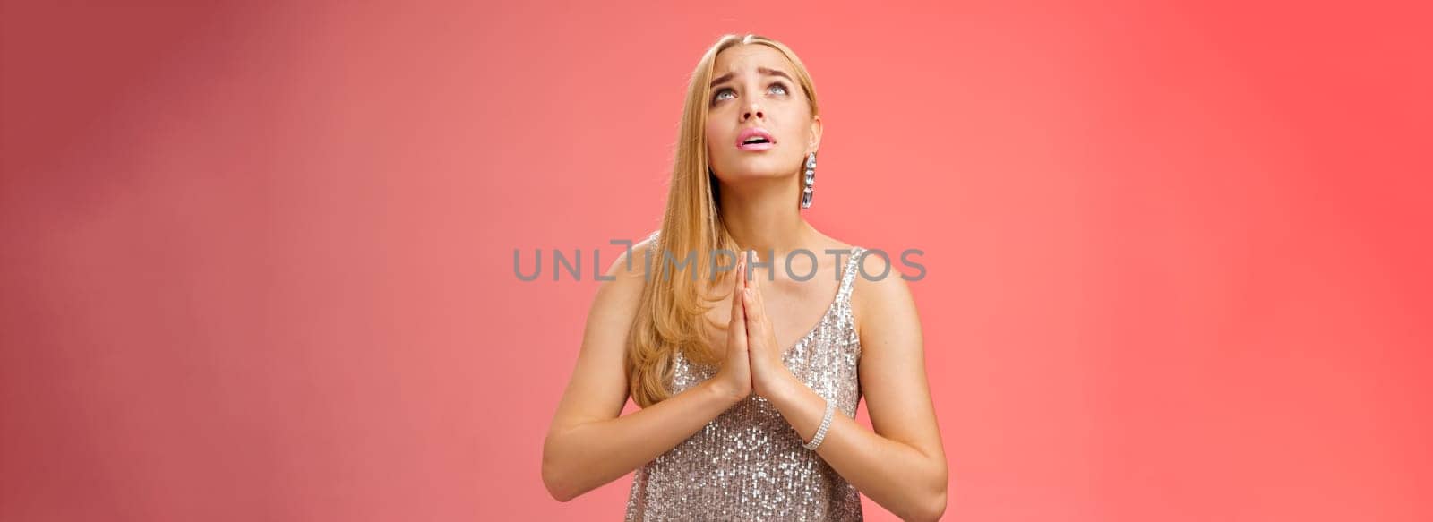 Hopeful worried concerned faithful blond woman in silver dress praying talking god wishing family okay press palms together supplicating nervously begging, standing red background stylish dress by Benzoix