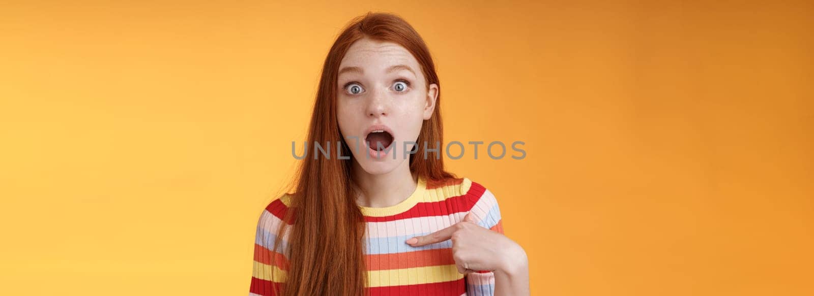 Shocked silly surprised redhead cute girl gasping drop jaw stunned stare camera full disbelief pointing herself cannot believe chosen picked participate event standing impressed orange background by Benzoix