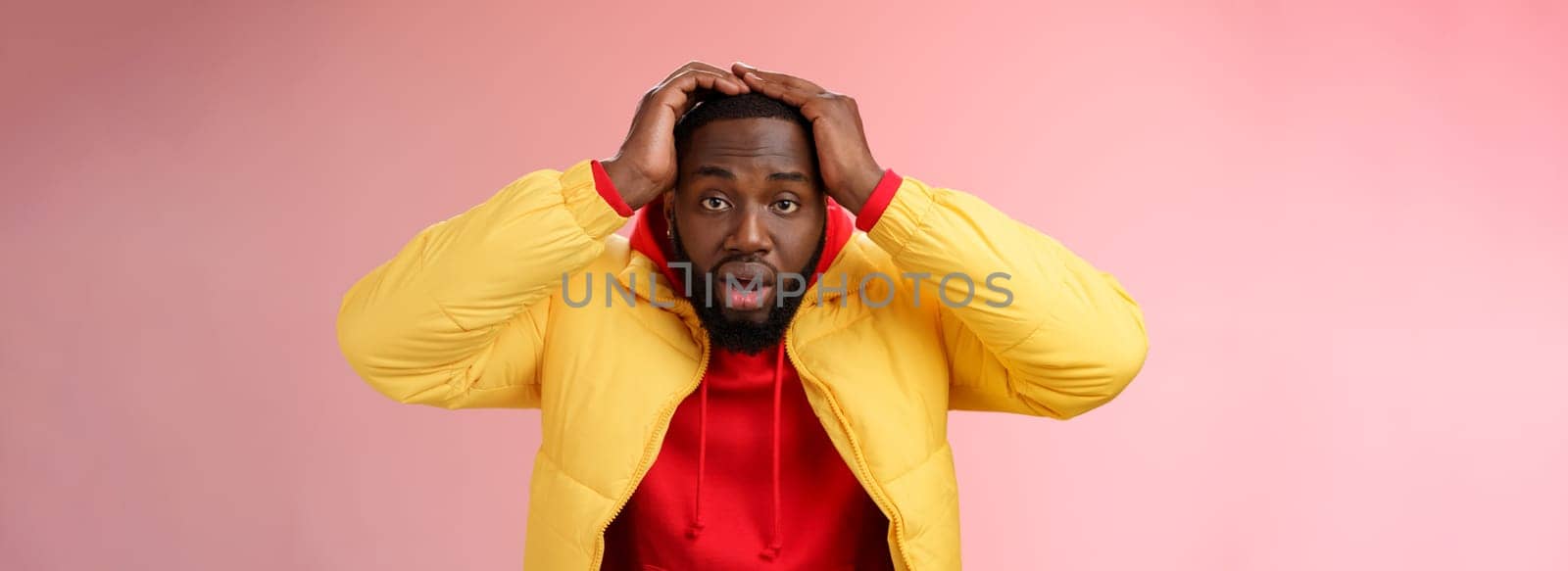 Shocked stupefied young african-american bearded man grab head drop jaw gasping confused frustrated looking upset troubled have problems standing stunned concerned pink background by Benzoix