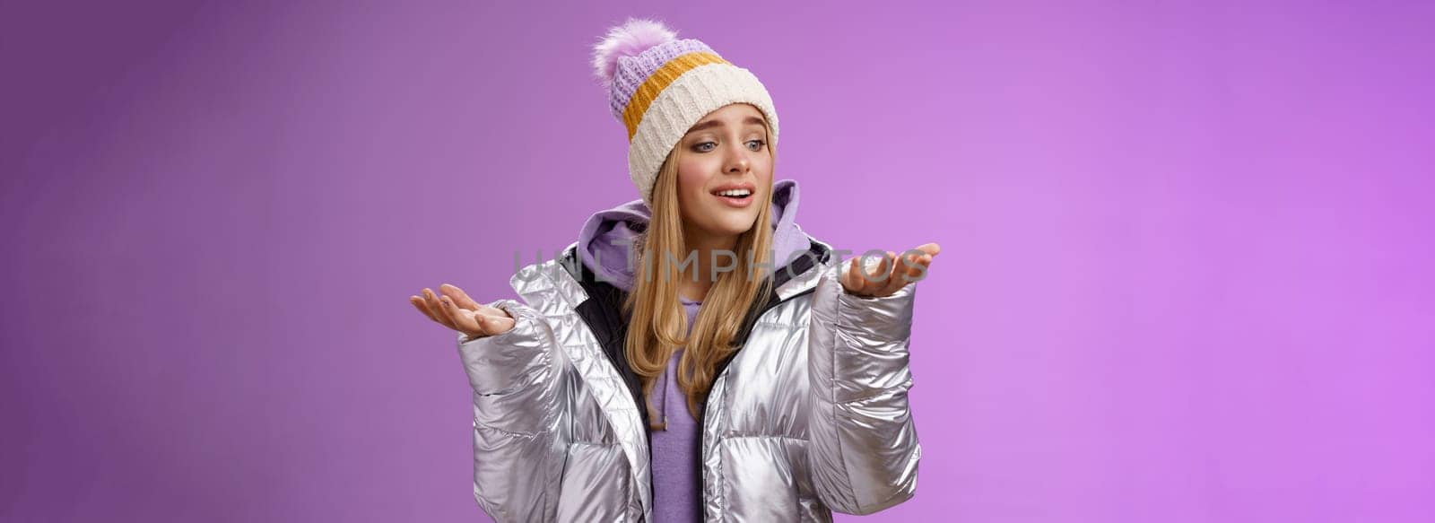 Delighted caring lovely young blond woman looking snowflake drop palm glancing hand tenderly smiling cherish nice moment enjoying winter snowy day standing pleased purple background.