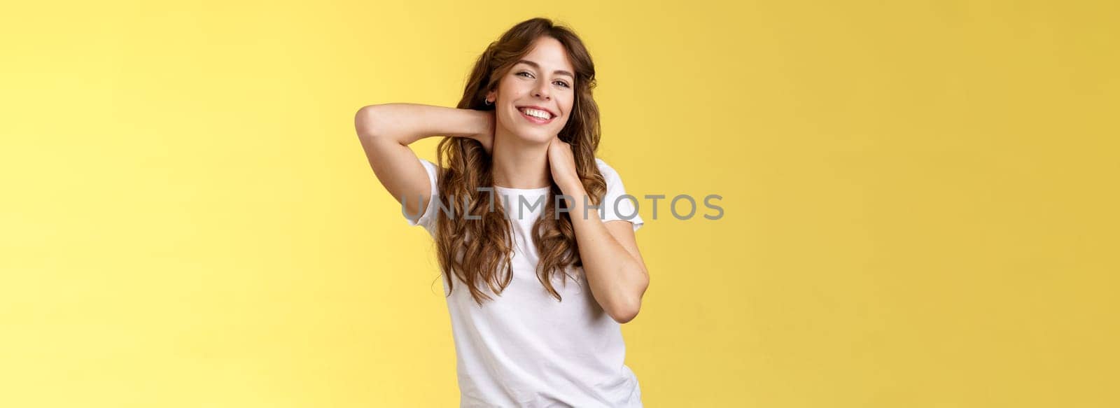 Cheerful charismatic good-looking curly-haired woman stretching posing yellow background touch neck flirty smiling relaxing perfect summer vacation booking weekend trip finally rest under sun by Benzoix