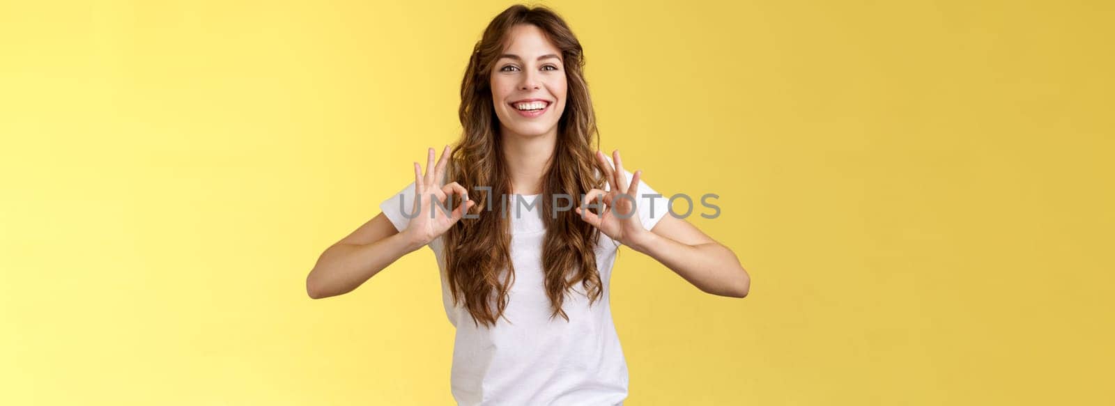 Deal I guarantee excellent results. Good-looking friendly pleasant young woman assure everything okay show ok perfect gesture smiling confident relaxed stand yellow background promise be good by Benzoix