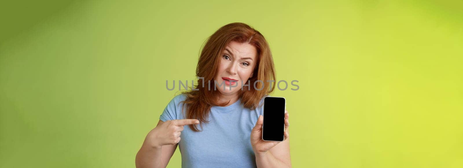 Have something say. Questioned serious-looking displeased redhead mature mother acting pissed hold smartphone pointing blank mobile phone screen demand answers found daughter social-media photos.