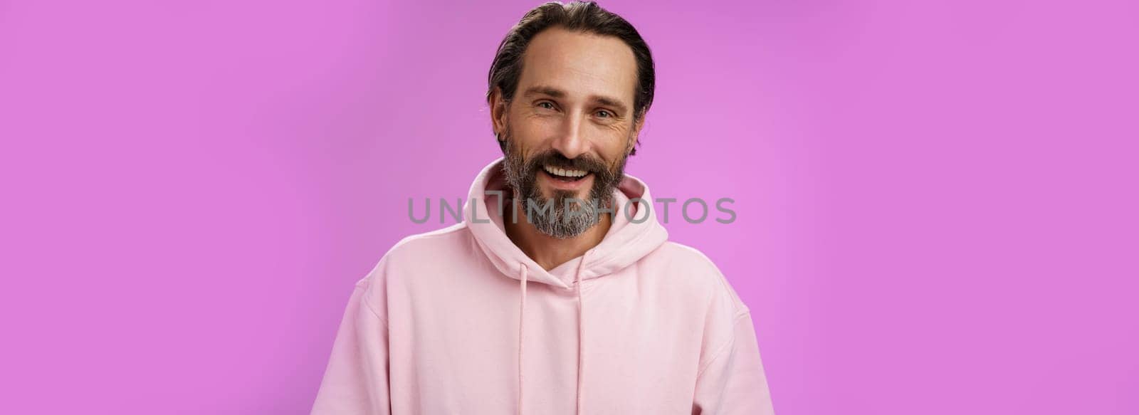 Close-up charming caring friendly-looking european bearded husband talking video chat wife working abroad smiling happy see family standing gladly purple background rejoicing enjoying conversation by Benzoix