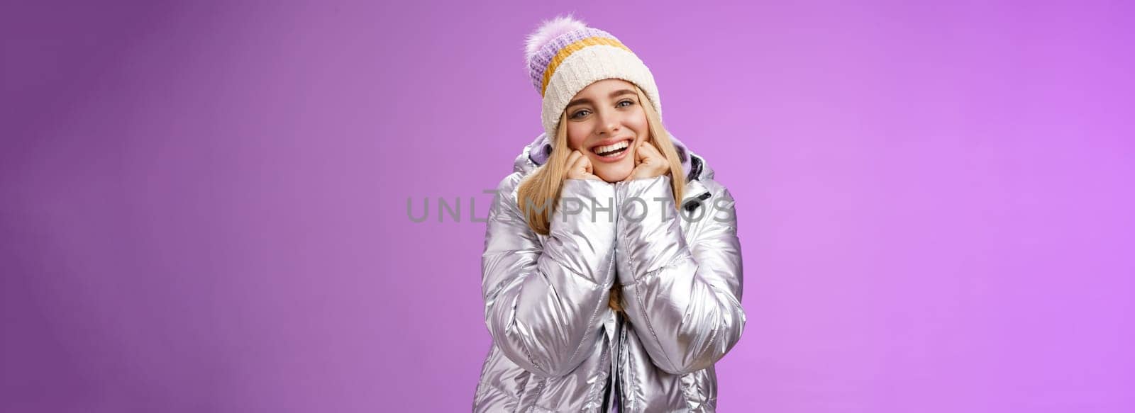 Lifestyle. Delighted charming tender female in stylish cute hat silver shiny jacket lean chin hands smiling sighing enjoying watching lovely romantic scene wanna fall in love standing happily purple background.