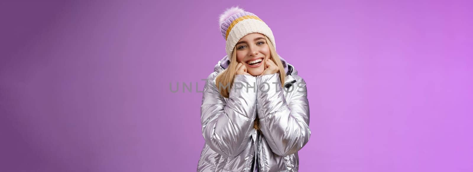 Delighted charming tender female in stylish cute hat silver shiny jacket lean chin hands smiling sighing enjoying watching lovely romantic scene wanna fall in love standing happily purple background by Benzoix