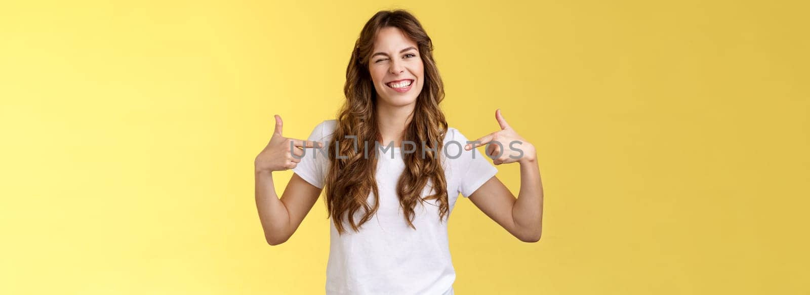 You would not regret this. Sassy good-looking outgoing daring young woman pointing center copy space indicating herself winking joyfully show perfect candidature stand yellow background.