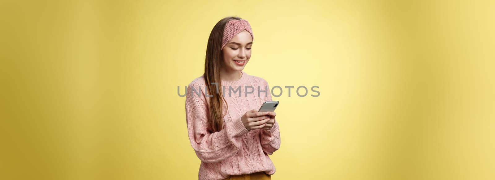 Girl chatting, texting, sending funny emoji friend smiling entertained holding smartphone looking device screen amused, enjoying playing with awesome app, watching video online via cellphone by Benzoix