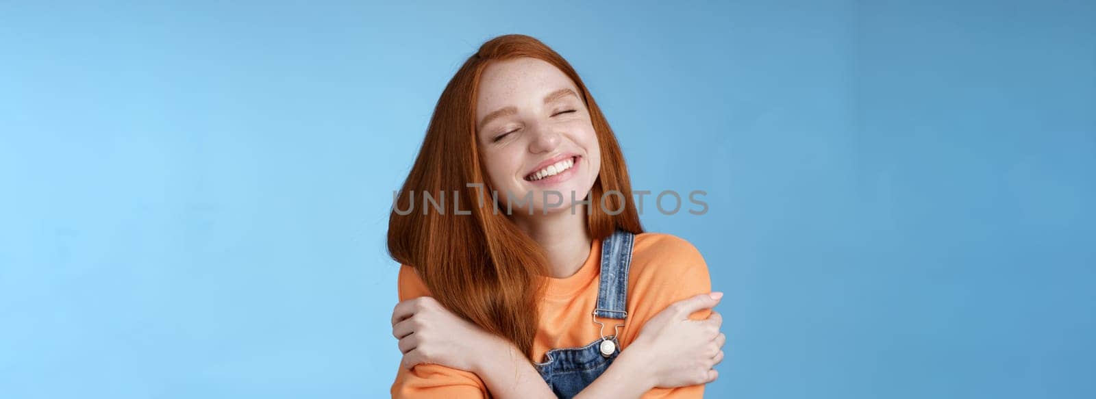 Lifestyle. Close-up dreamy happy smiling redhead girl close eyes fantasizing romantic date grinning white teeth cuddle herself cross arms chest embracing recalling lovely memories hugging daydreaming.