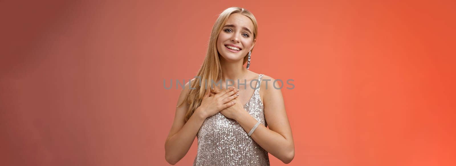 Touched delighted charming blond woman receive heartwarming pleasant gift smiling glad press palms heart moved thanking cherish romantic move boyfriend made, standing red background by Benzoix