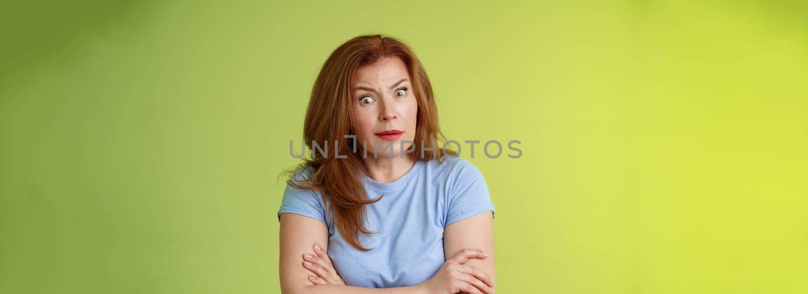 You did what. Confused shocked speechless redhead mature mother stare camera puzzled concerned cross arms chest self-soothing bothered pose look questioned hesitant green background by Benzoix