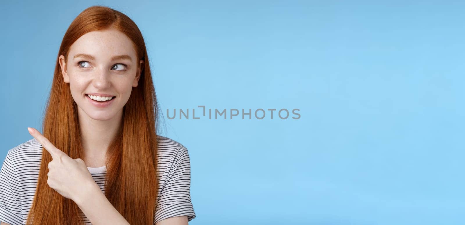 Intrigued good-looking redhead joyful curious girl watching looking upper left corner interested smiling broadly visit cool amusing place explore travelling new country astonished, blue background by Benzoix