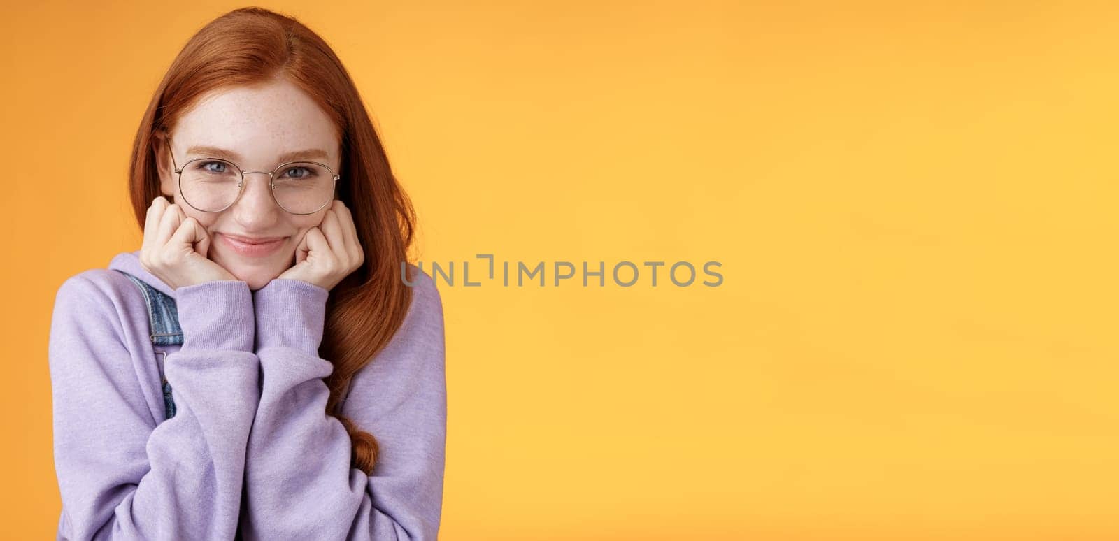 Lovely cute redhead sweet silly girl geek university student wearing glasses lean hand smiling tenderly look affection adore listen sensual confessions boyfriend, standing orange background.