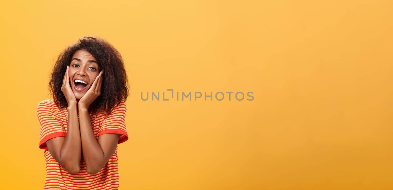 Dreamy good-looking stylish young african female with curly hairstyle sighing leaning head on palms gazing with affection and admiration at camera being in love imaging prince on white horse. Lifestyle.