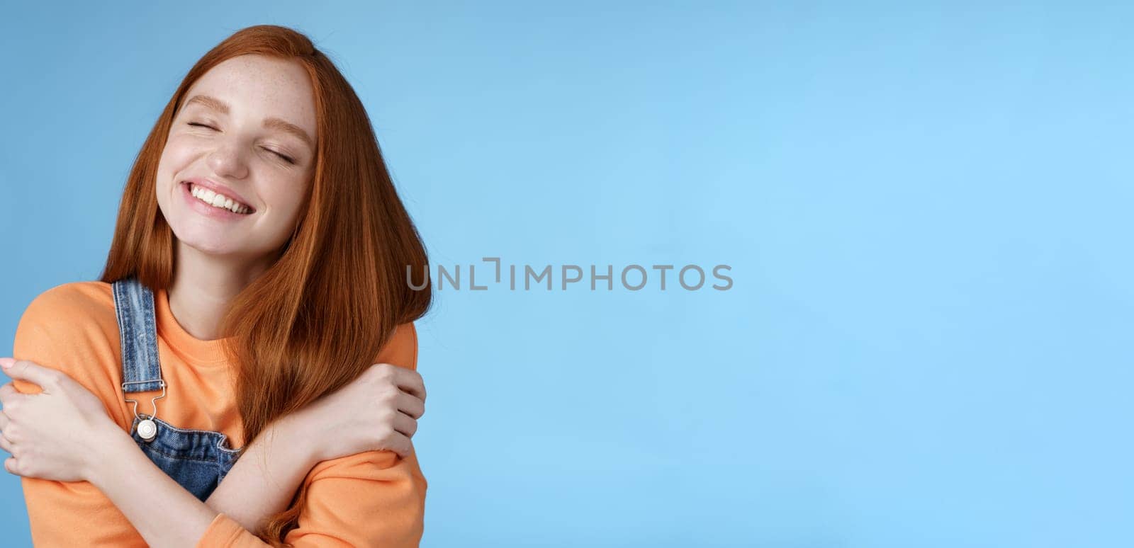 Close-up dreamy happy smiling redhead girl close eyes fantasizing romantic date grinning white teeth cuddle herself cross arms chest embracing recalling lovely memories hugging daydreaming by Benzoix