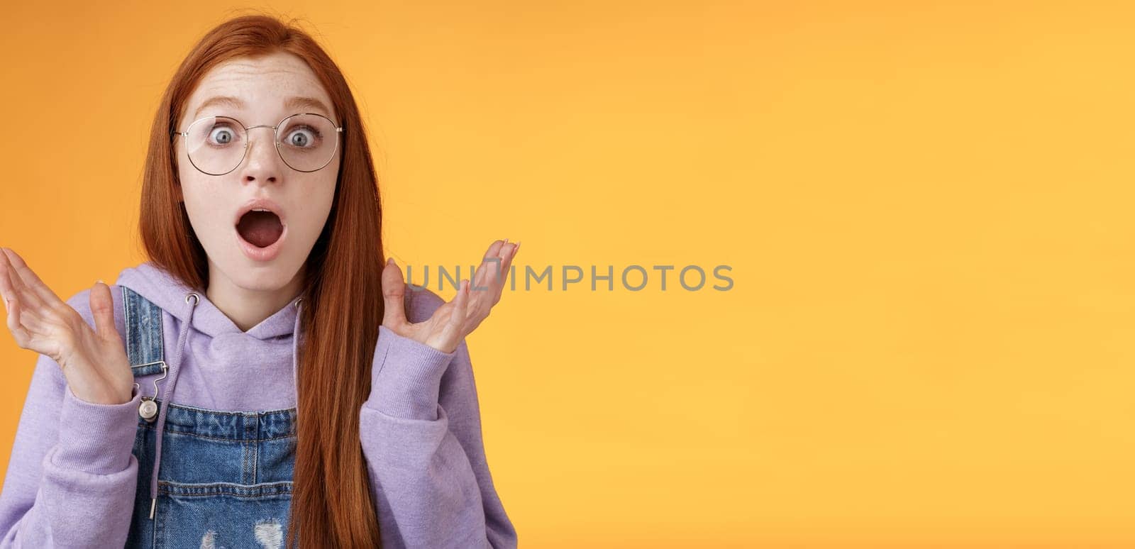 Close-up shocked sensitive concerned young panicking redhead woman worry drop jaw gasping raise hands spread freak out stare surprised emotional reacting incredible news, orange background by Benzoix