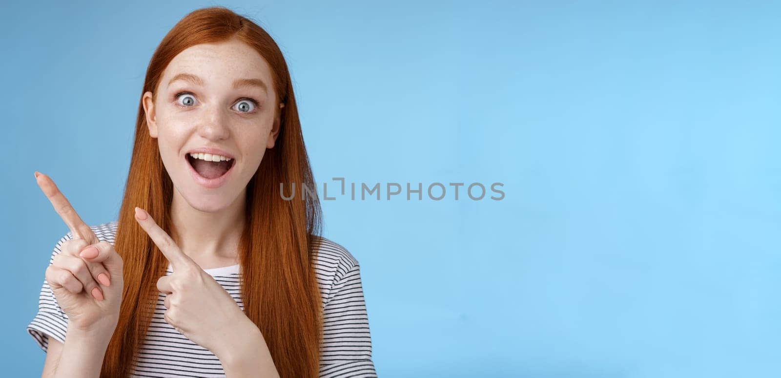 Lifestyle. Charismatic impressed surprised good-looking happy smiling cute redhead girl say wow grinning astonished wide eyes pointing upper left corner stunned thrilled speechless see awesome promo.