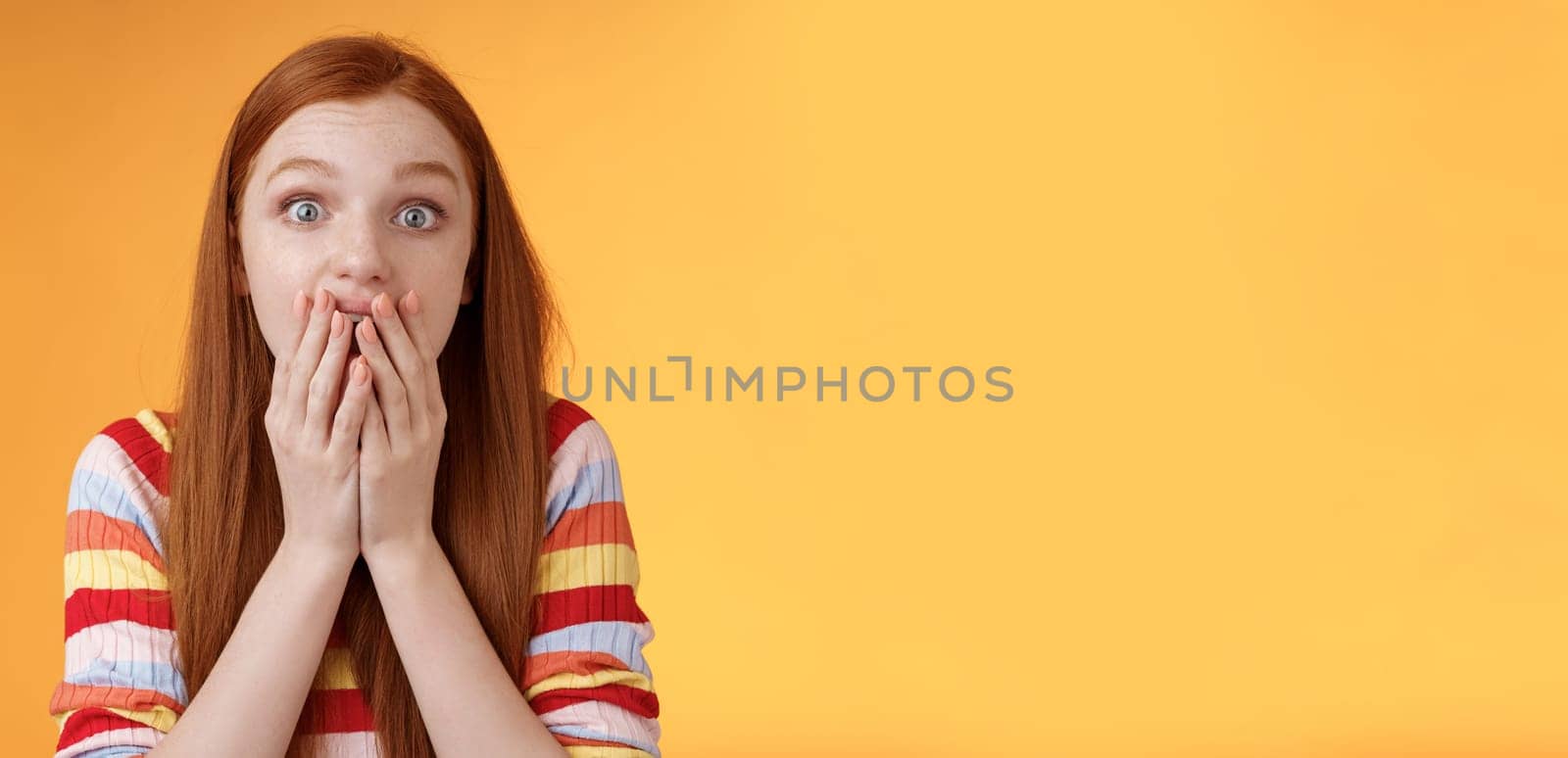 Excited shocked redhead speechless girl like gossiping standing emotional astonished hear amusing story gasping full disbelief cover mouth palm amazed posing orange background impressed.