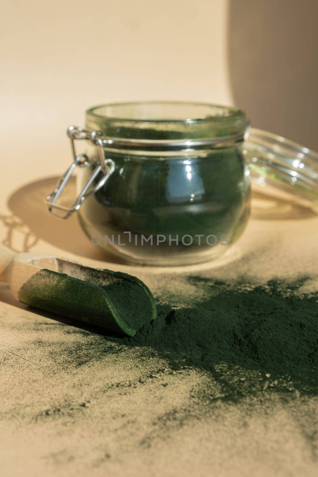 Organic blue-green algae spirulina powder food in glass jar with wooden spoon. Health benefits of spirulina chlorella. Dietary supplement superfood concept