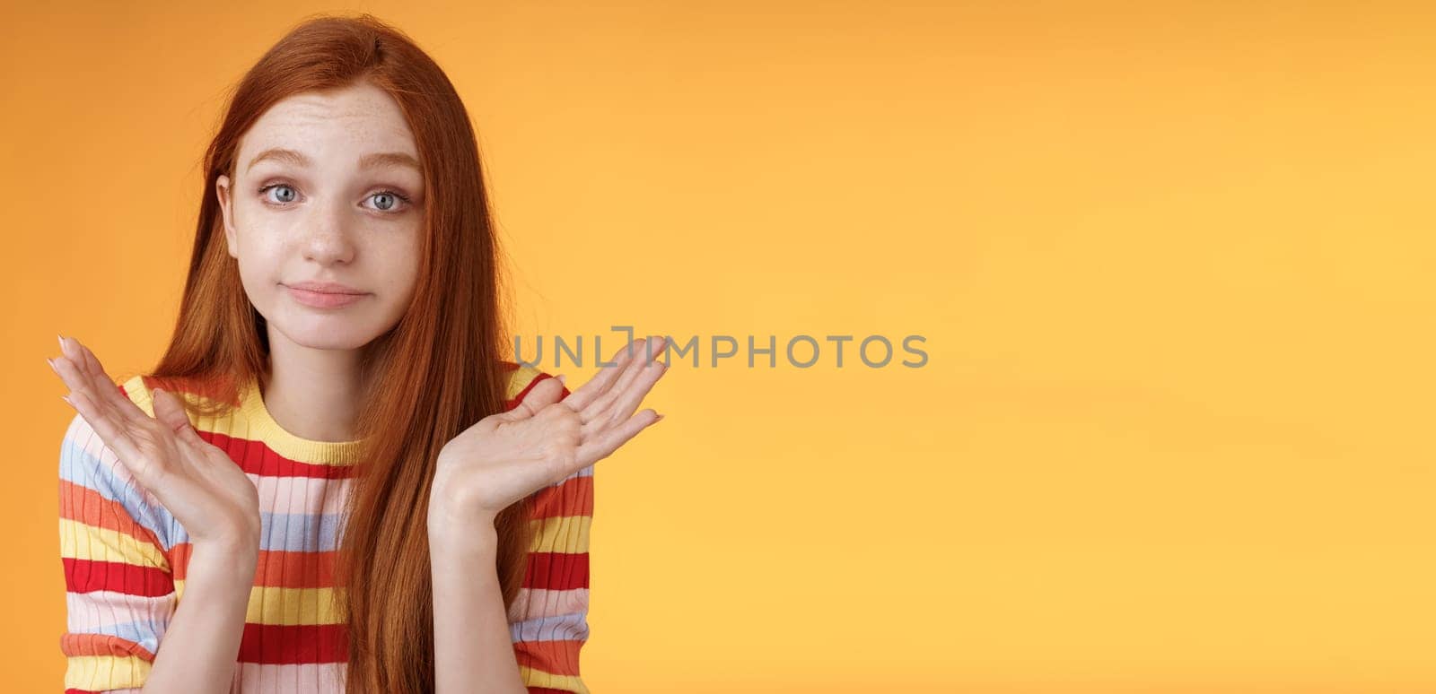 Clueless unbothered young redhead silly european girl 20s shrugging hands spread sideways smirking sorry cannot answer standing unaware confused puzzled give reply, orange background by Benzoix