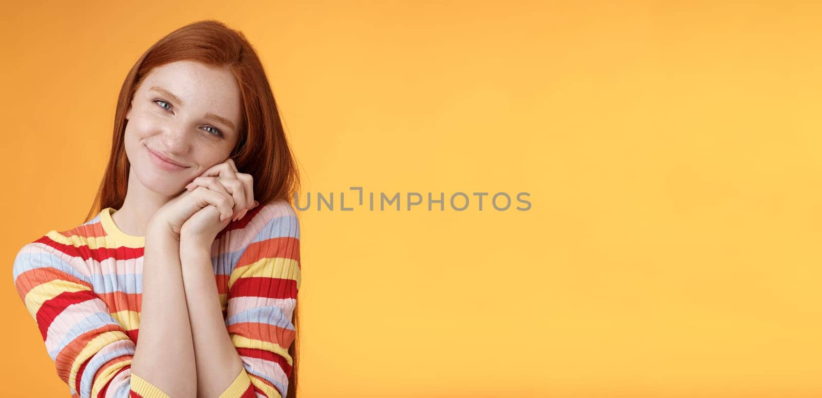 Sweet silly tender redhead young girl leaning palms touched smiling receive charming lovely gift standing thankful look affection sympathy accept dearest romantic gesture, orange background by Benzoix