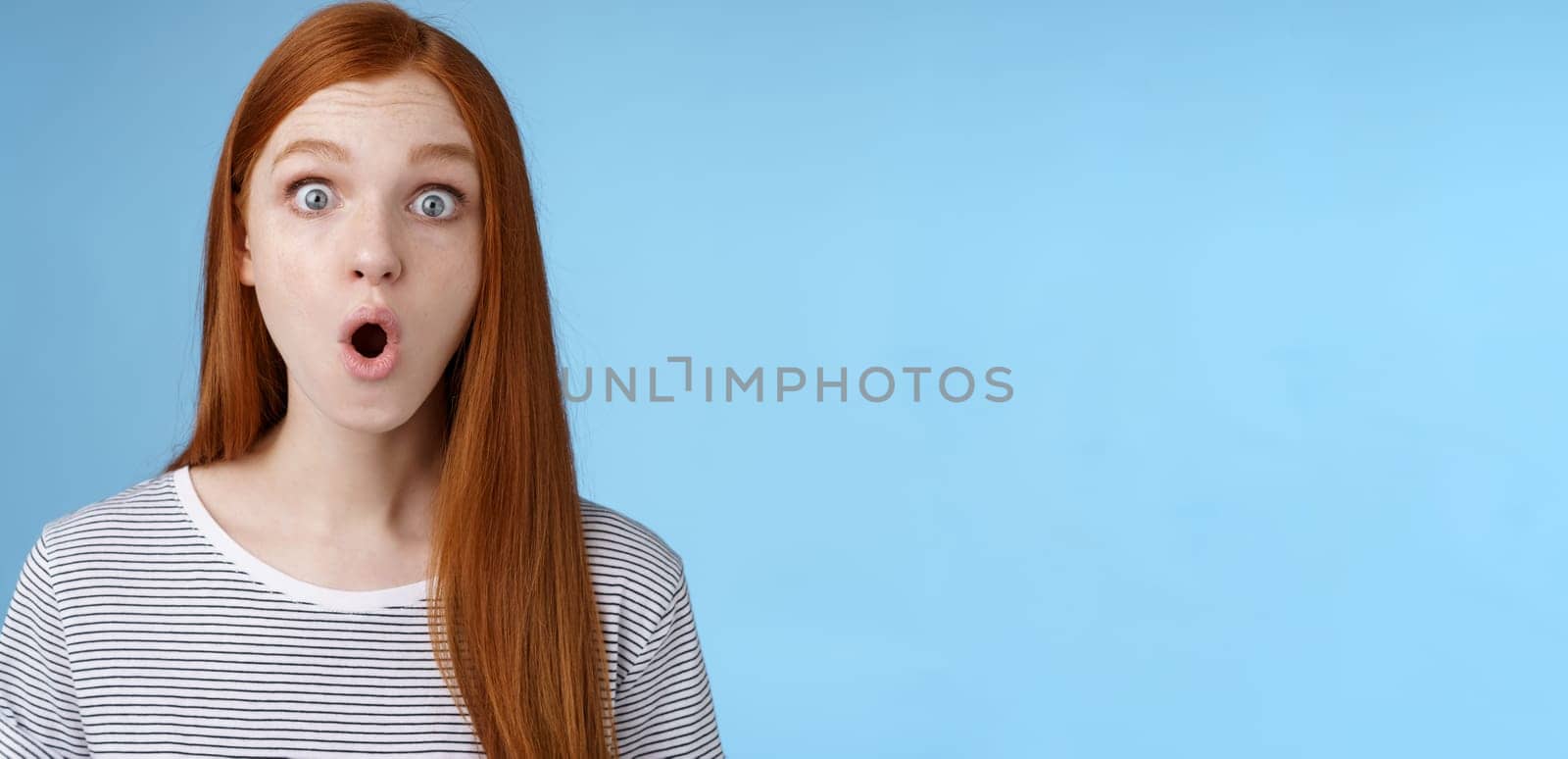 Wow omg fascinating. Impressed surprised amused good-looking redhead girl folding lips astonished wide eyes stunned reacting incredible cool promo standing blue background speechless by Benzoix