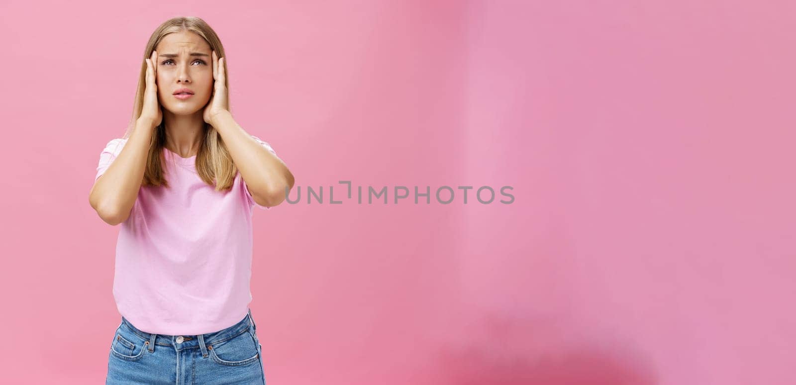 Woman trying recall important number touching temples with hands looking up concerned and focused having trouble to remember information standing intense against pink background. Body language and emotions concept