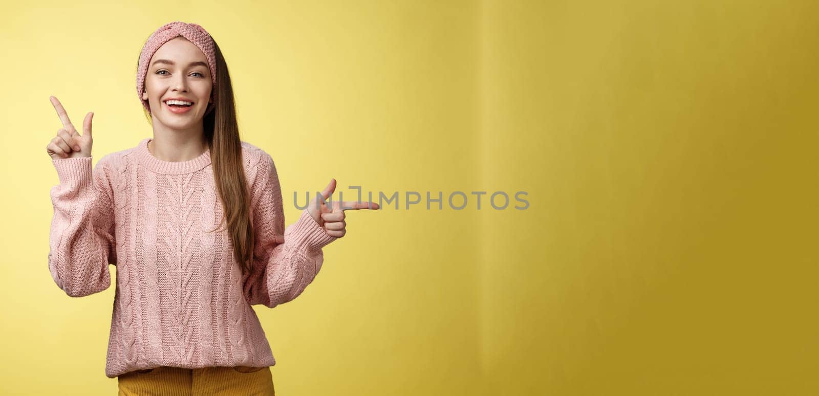 Pick what want. Charismatic cheerful young female student in headband, sweater pointing up, indicating right smiling cute, promoting advertisement showing opportunities and choices over white wall.