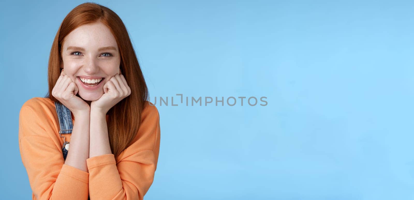 Lifestyle. Enthusiastic sassy good-looking redhead caucasian girl lean head palms look amused intrigued listen interesting story pleased smiling laughing silly jokes standing blue background excited happy.