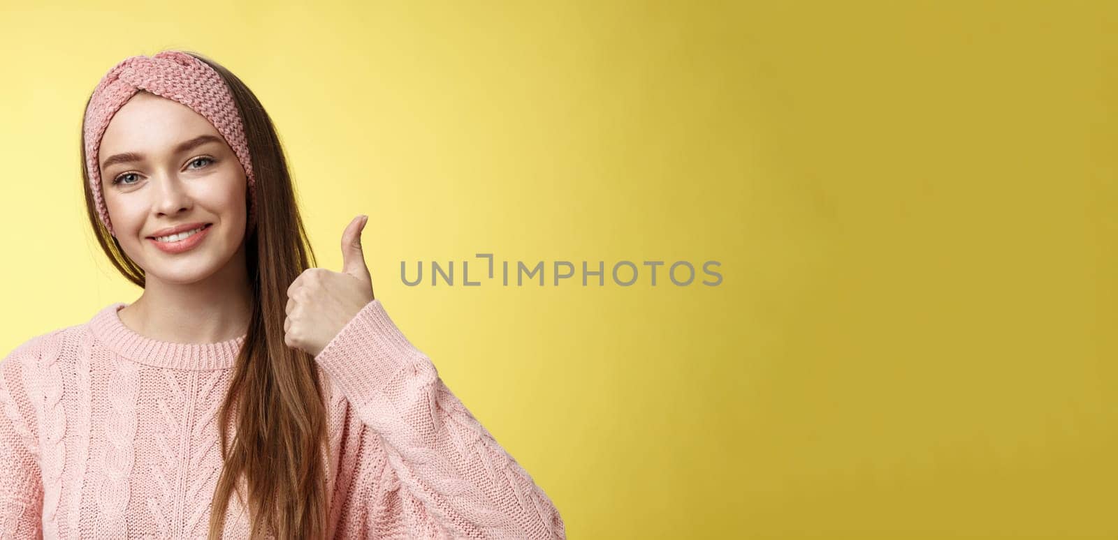 Pretty european young girl in headband, pink sweater smiling delighted, pleased showing thumbs up in agreement, approval, giving good recommendation, liking interesting great idea smiling cheerful by Benzoix