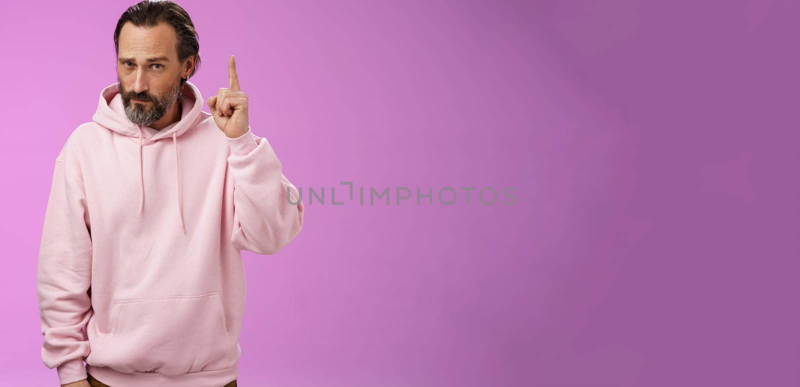 Strict serious-looking stylish bearded father teaching scolding teenage son raising index finger frowning displeased disappointed bad child behaviour, make statement, standing purple background by Benzoix