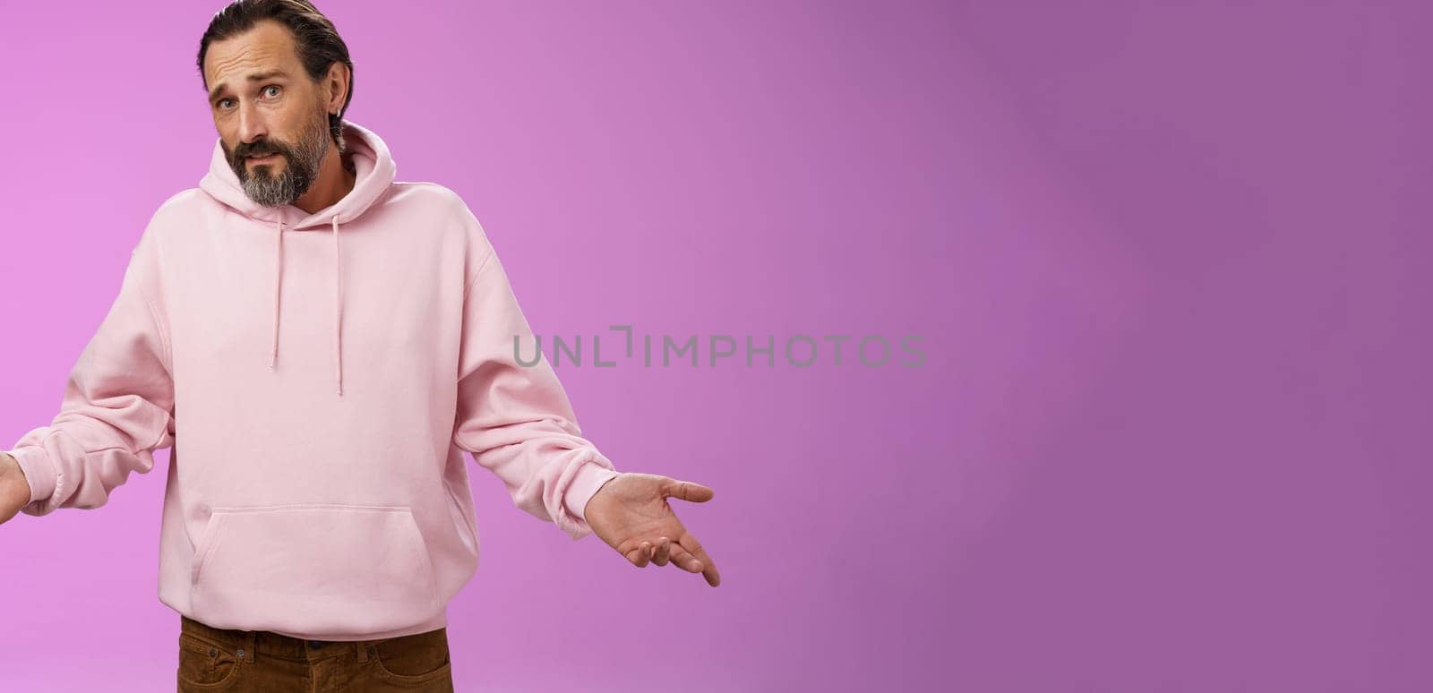 Nothing man could do. Mature bearded guy grey hair 40s spread hands dismay cannot help gesture frowning apologizing shrugging unaware standing perplexed not know anything, purple background.