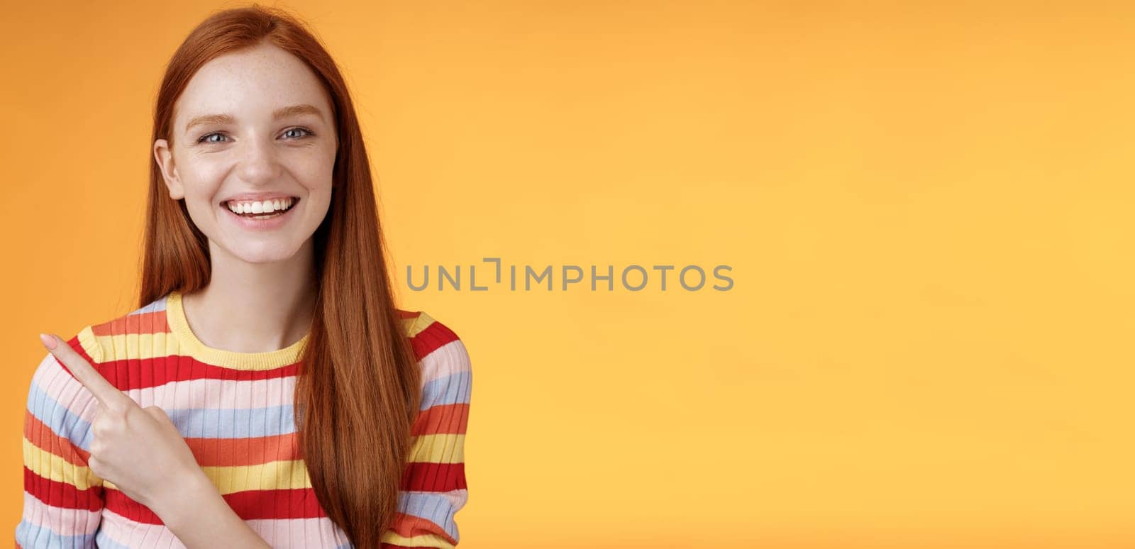 Happy charismatic smiling young ginger girl blue eyes sincere tender grin laughing broadly having fun discuss hilarious concert pointing upper left corner showing awesome product, orange background by Benzoix