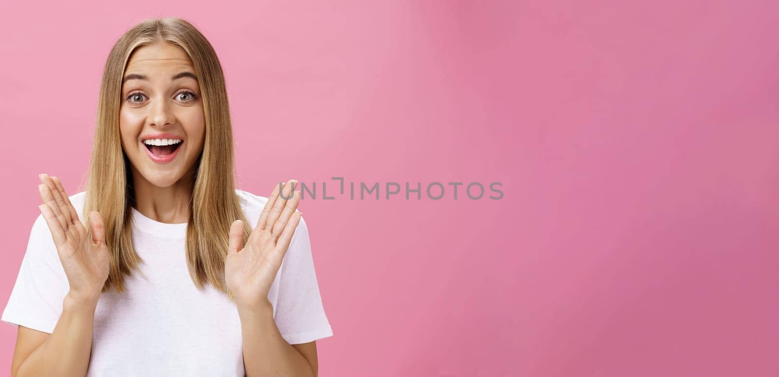 Woman learning awesome great news clasping hands in joy and excitement rejoicing feeling hapyp for friend smiling broadly and looking cheerful at camera with amused expression over pink background. Body language and emotions concept