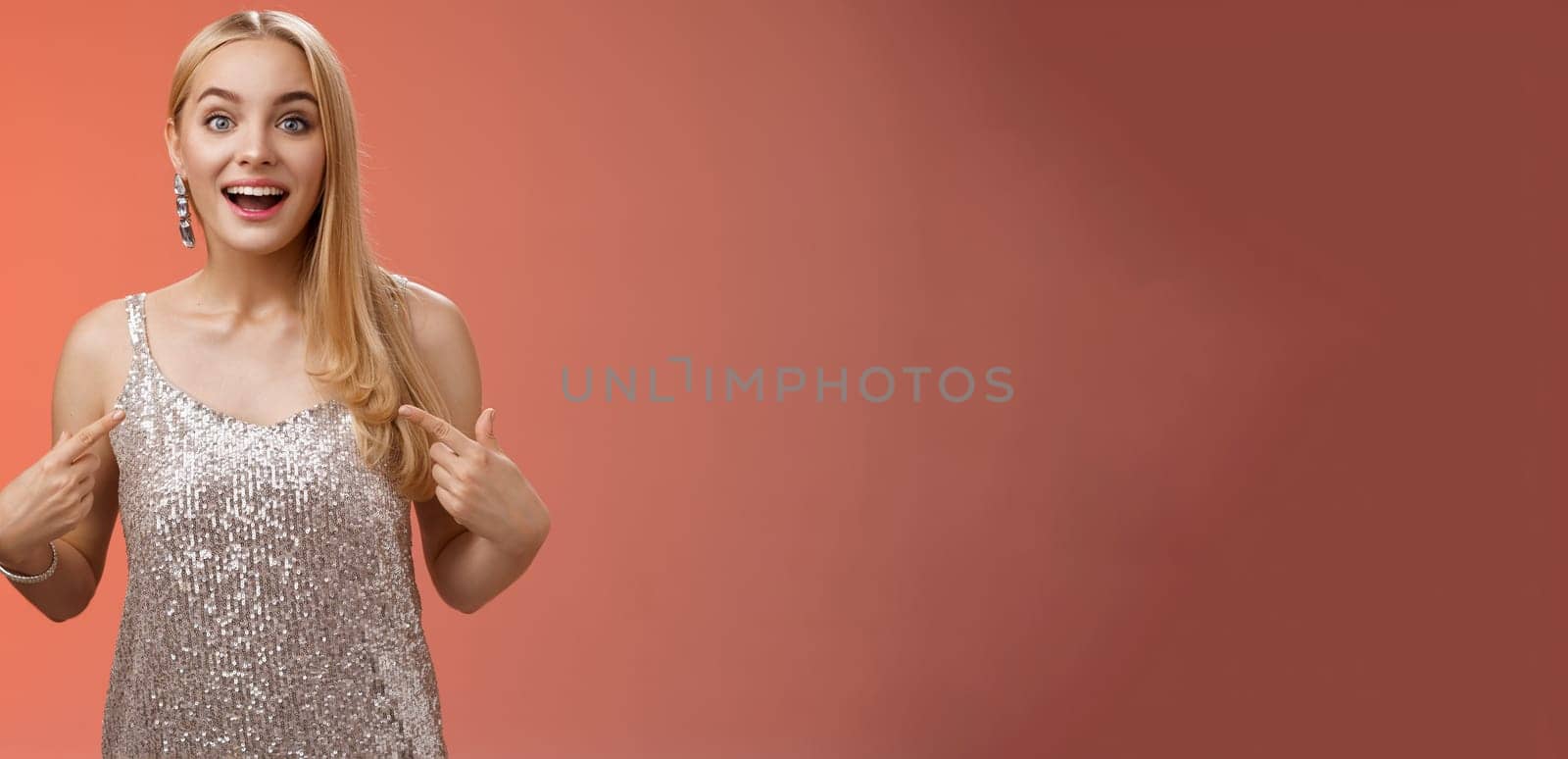 Surprised wondered happy blond charming cheerful woman in glittering silver dress pointing herself amused thrilled picked be chosen participate awesome event, standing joyful red background.