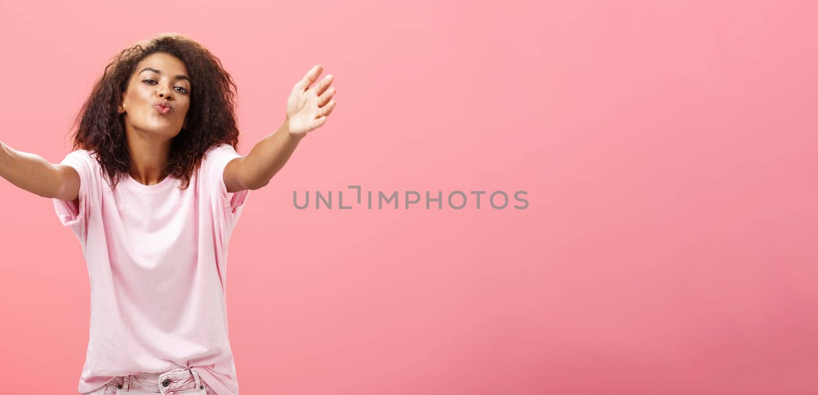 Come closer let me hug you. Portrait of passionate confident and happy good-looking african american woman with curly hairstyle folding lips pulling hands towards camera to cuddle and give kiss. Relationship and feelings econcept