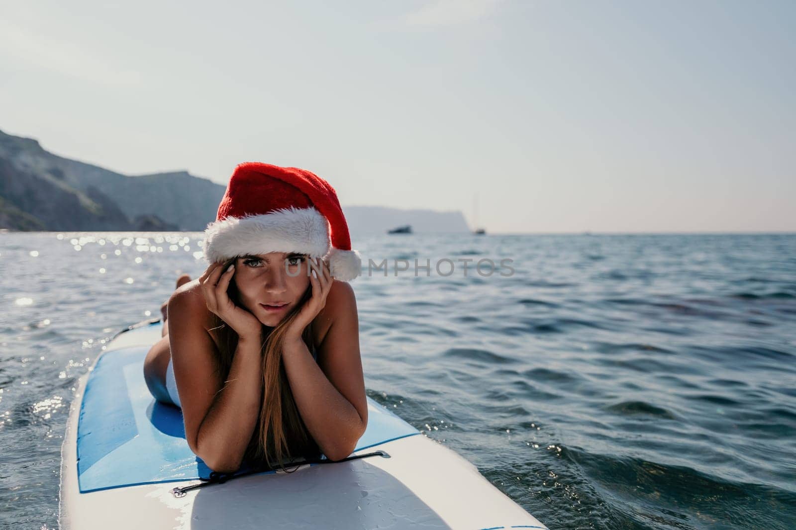 Close up shot of happy young caucasian woman looking at camera and smiling. Cute woman portrait in bikini posing on a volcanic rock high above the sea